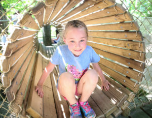 a girl at the end of a wooden tunnel smiling