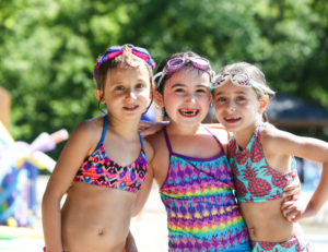 three girls smiling before getting into the pool