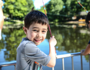 a boy looking at the camera with a fishing rod