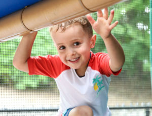 a boy in a play structure waving