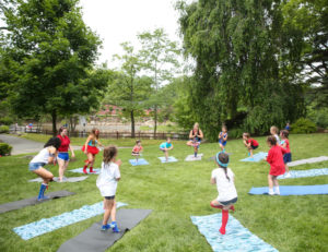 A group of campers in a circle doing yoga outside
