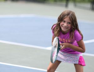 A girl smiling while holding a tennis racket