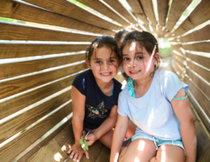 Two girls in a wooden tunnel smiling