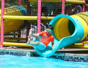 A boy with goggles exiting a waterslide