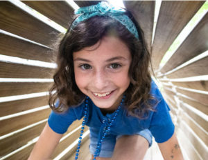 an up close image of a girl happily climbing through a tunnel