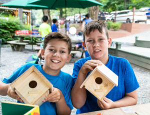 two boys holding up birdhouses