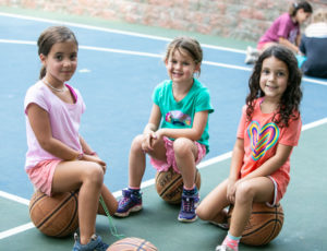 three girls sitting on basketballs