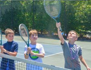 three boys holding tennis rackets