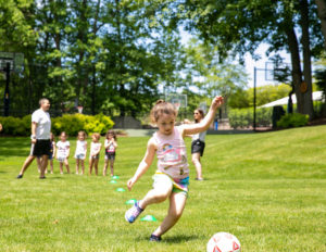 a young girl running to kick a soccer ball