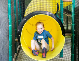 a little boy edging out of a slide