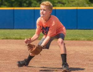 A boy crouching to catch a ball with a mitt