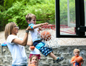 a counselor lifting a boy up to reach the basket