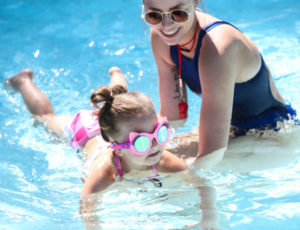 a counselor helping a young girl learn to swim