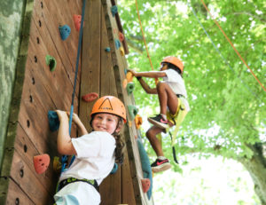 a girl smiling at the camera on a climing wall