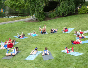 a group of campers in a yoga pose on the ground outside