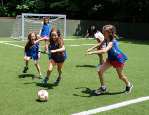 girls running to kick a soccer ball