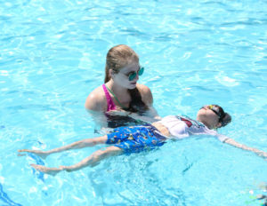a counselor helping a young boy learn to swim