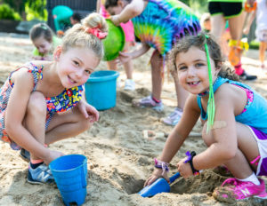 two girls digging a hole in sand