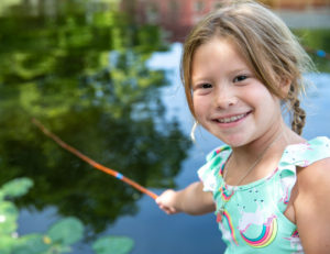 a girl smiling while holding a fishing rod