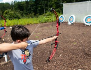 a boy aiming his bow and arrow at a target