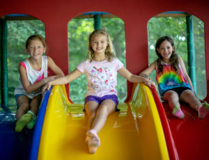 three girls posing at the top of a slide