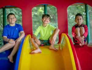 three boys posing at the top of a slide