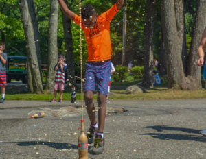 a boy jumping back from a bottle rocket exploding